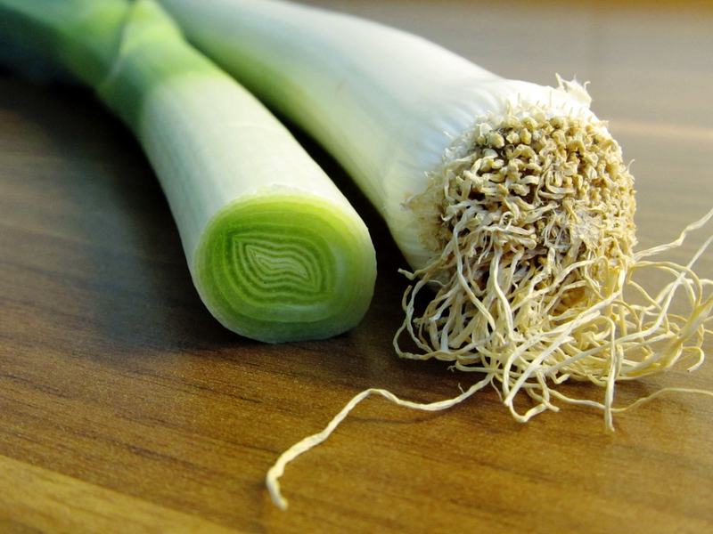 Leeks, one cut to show its layered white stalk